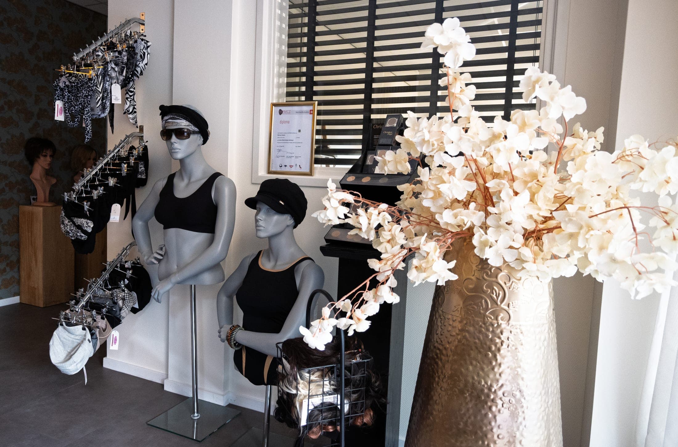 Chemomutsjes en badkleding op mannequins in de zaak van Hair Professionals.