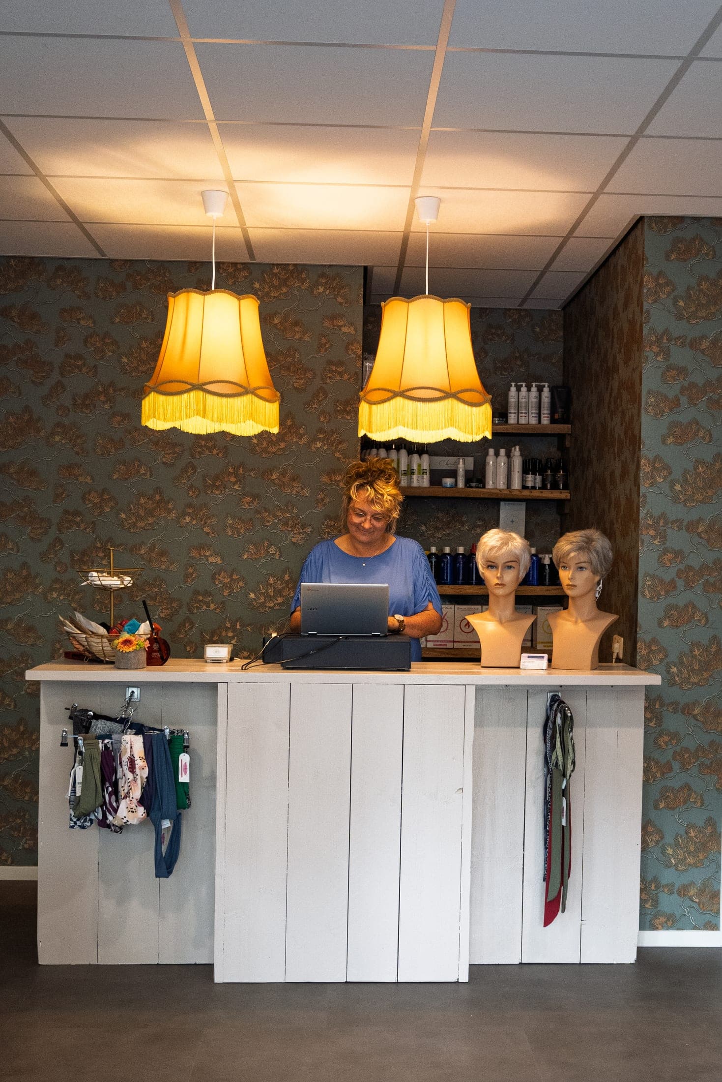 De eigenaresse van Hair Professionals aan de balie in de zaak, aan het werk.